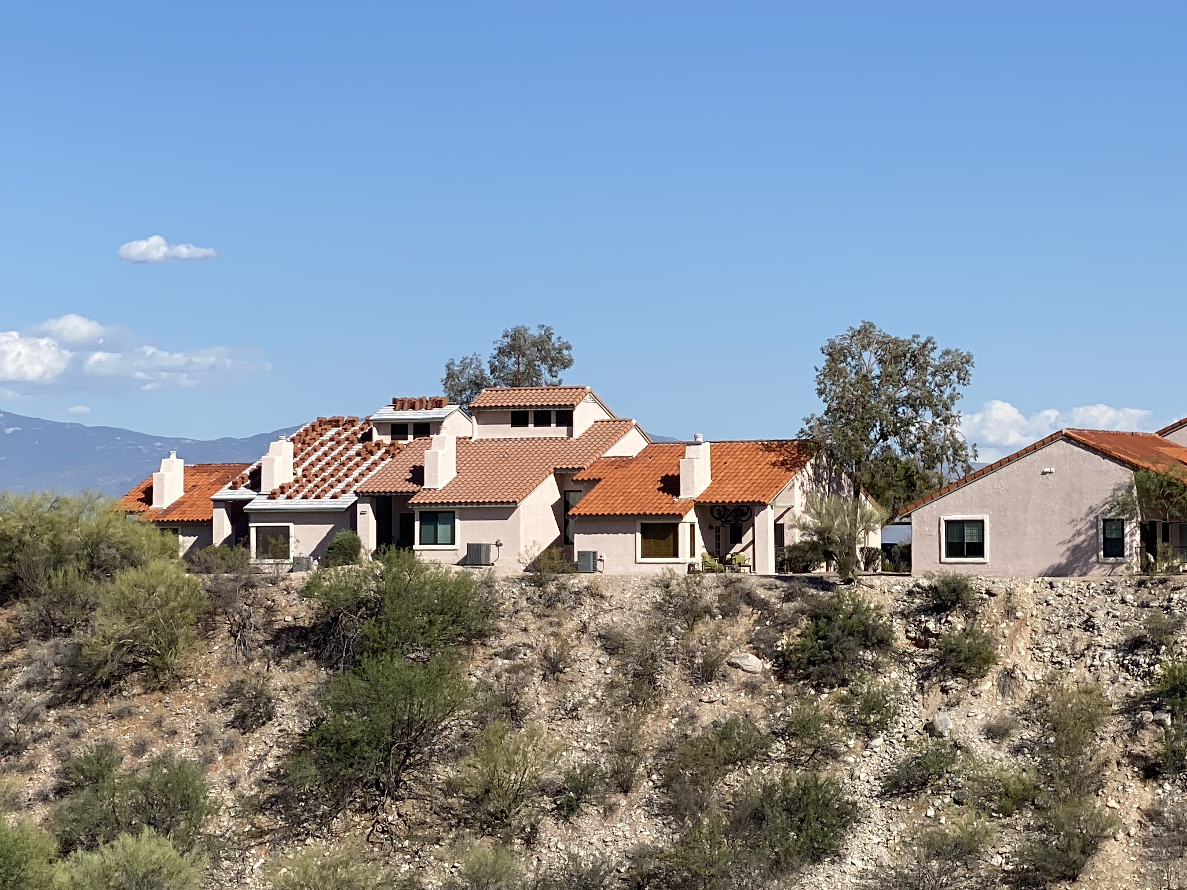 Tierra Catalina Condominiums viewed from below, with desert foliage, terracotta rooftops, and the Santa Catalina Mountains behind